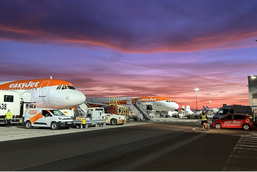 a airport runway with easyjet planes on it with a sunset in the background.